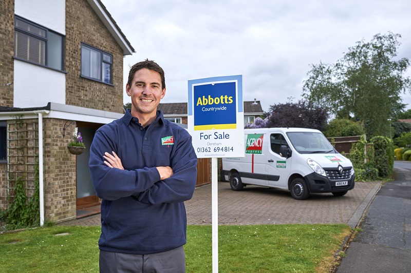 Agency Express franchisee standing in front of a house for sale sign