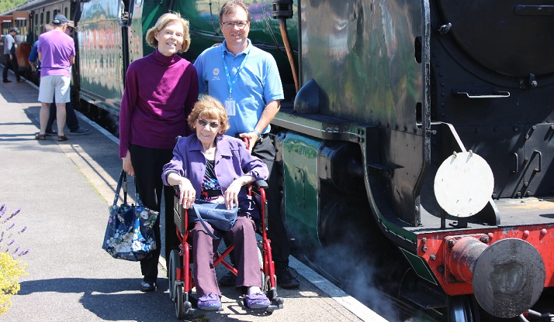 Driving Miss Daisy franchisee with customers next to steam train