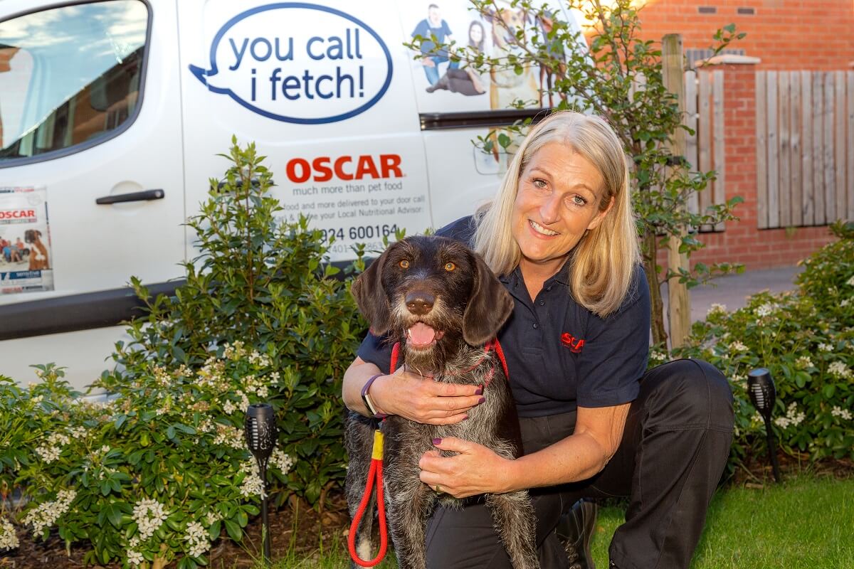 oscar pet foods franchisee hugging a dog infront of their van