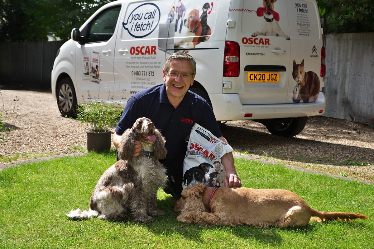 oscar pet foods franchisee hugging two dogs infront of their van