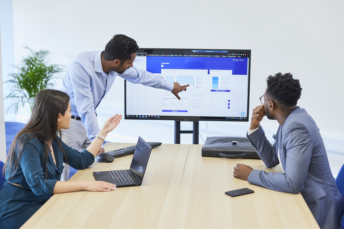 A Man presenting a on a screen while a lady and another man watch on