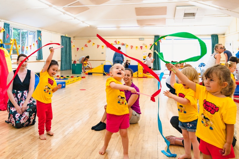 children playing with ribbons in a Tumble Tots class