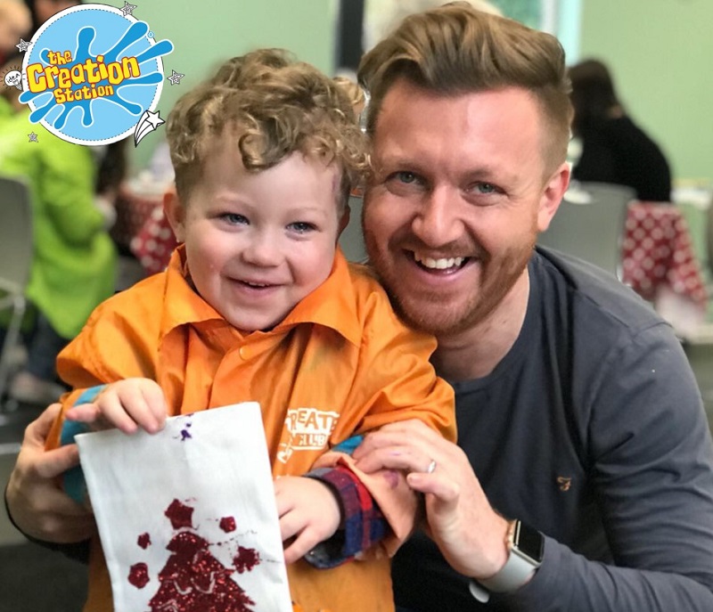 little boy showing his dad a picture he made at the Creation Station